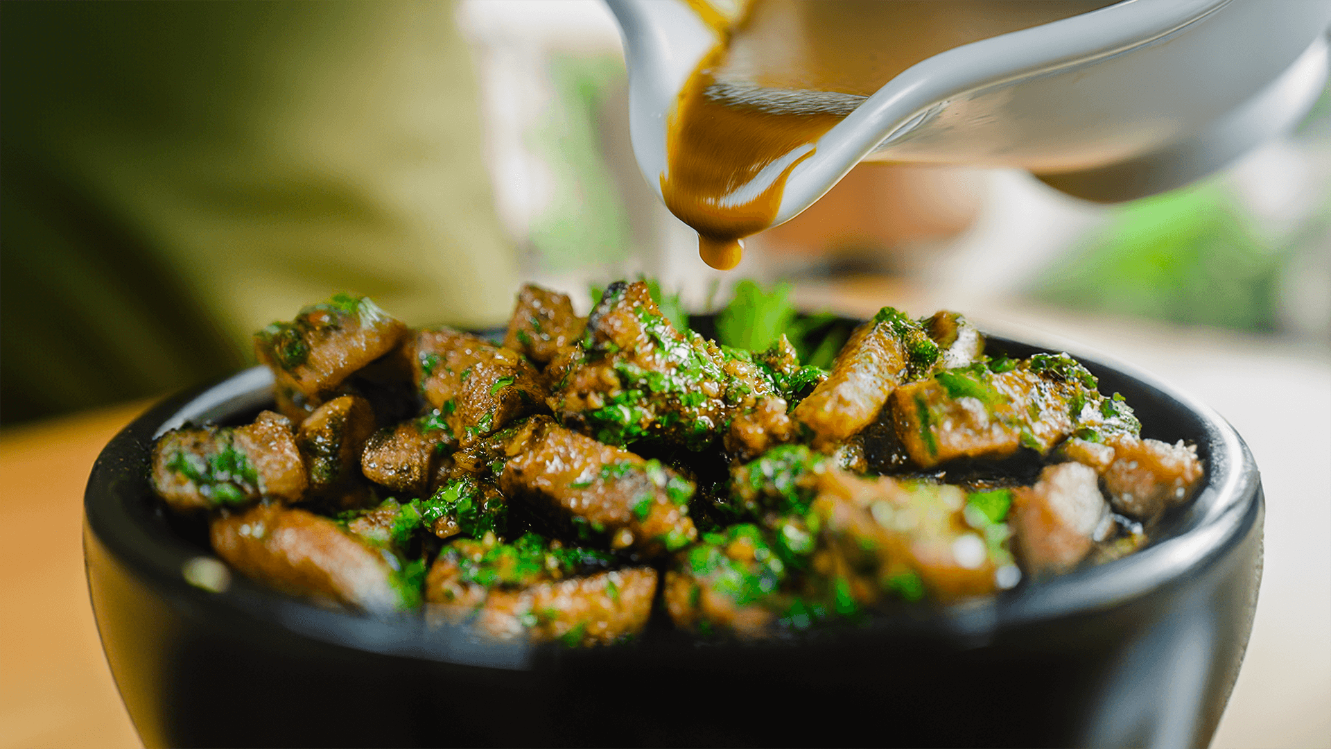 Leckere Knoblauch-Steak-Würfel mit herzhaftem Sauce beträufelt in einer schwarzen Schüssel, perfekt für ein FIVI-Rezept.