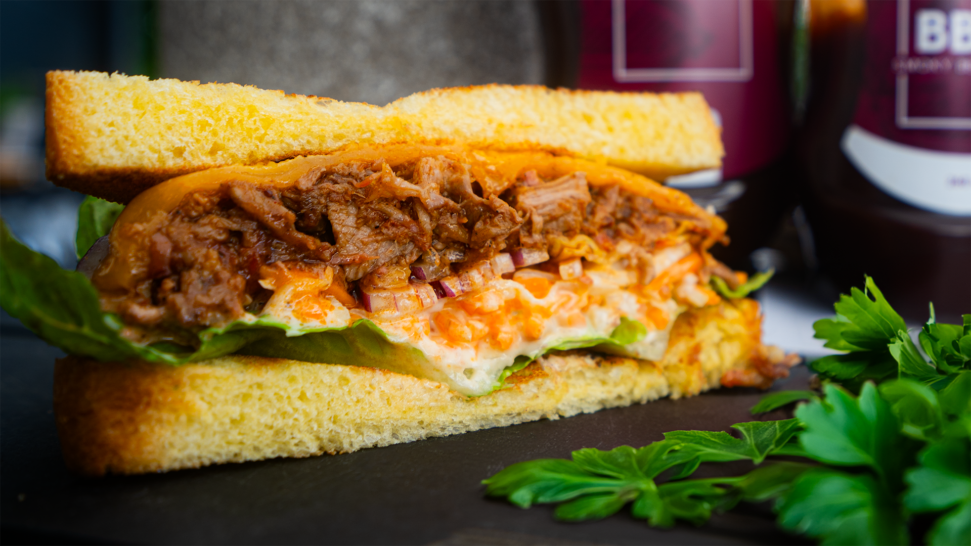 BBQ Pulled Pork Sandwich mit FIVI BBQ Sauce, serviert auf einem weichen Brötchen mit frischem Salat, knusprigem Brot und saftigem, gezupftem Schweinefleisch