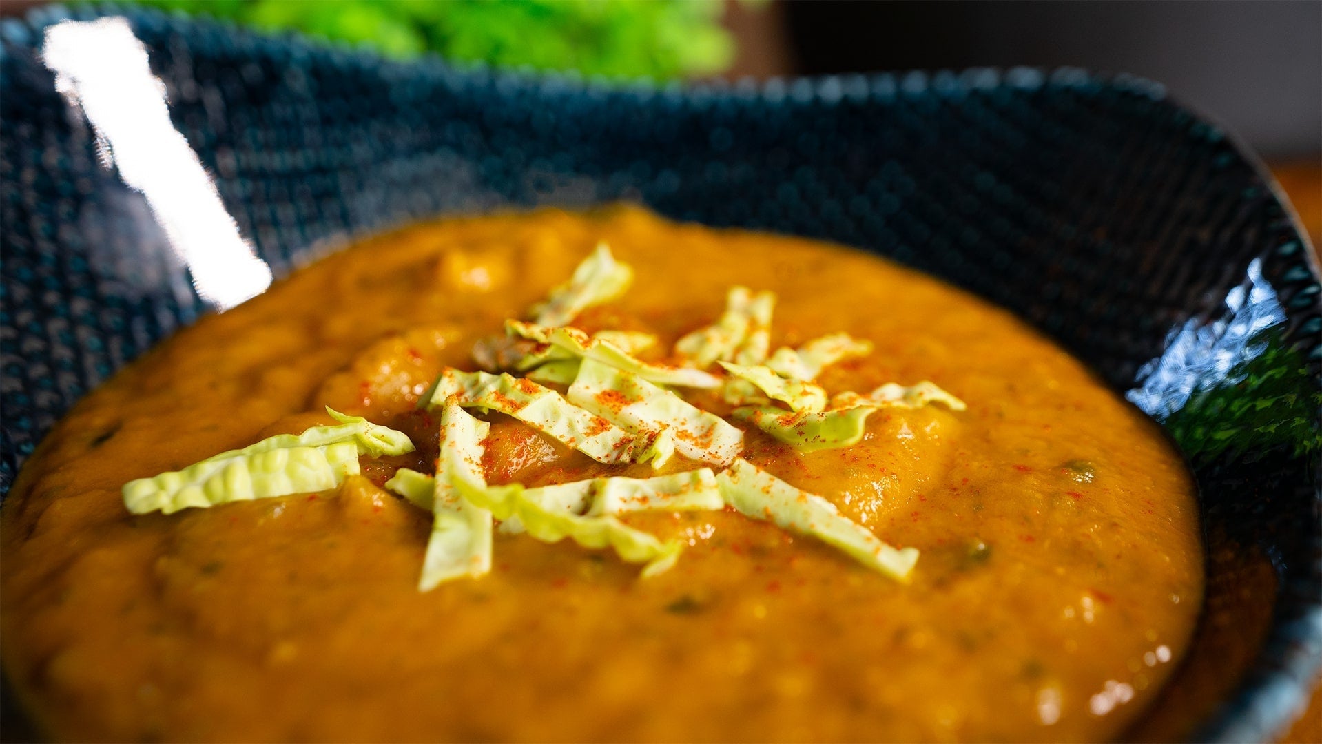 Nahaufnahme von cremigem Erdnuss-Wirsing-Eintopf, dekoriert mit Wirsingstreifen, serviert in einer Schale – gesundes veganes Rezept.