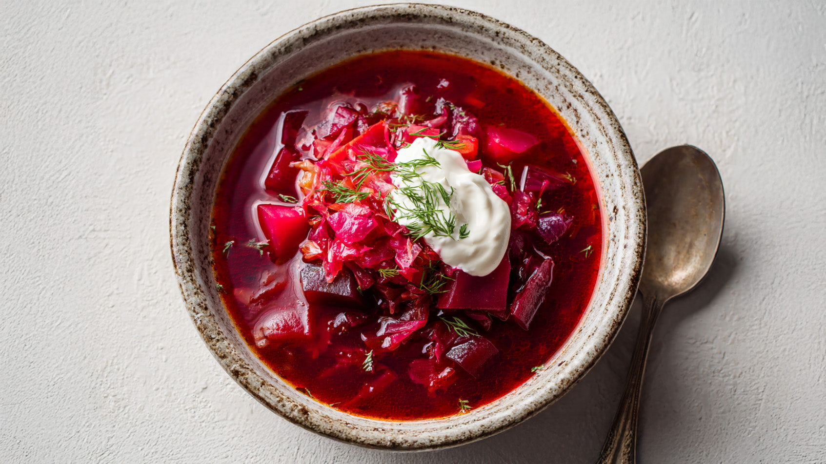 Borschtsch Rezept mit Roter Beete – leuchtend rote vegetarische Suppe mit Gemüse, Dill und cremigem Schmand in rustikaler Keramikschale