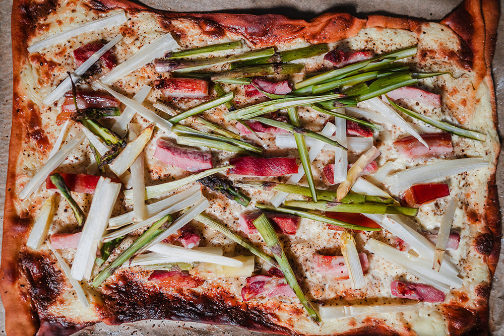 Spargel-Speck Flammkuchen mit grünem Spargel, Speck und Crème fraîche auf knusprigem Boden – frisch gebacken und mit Petersilie garniert