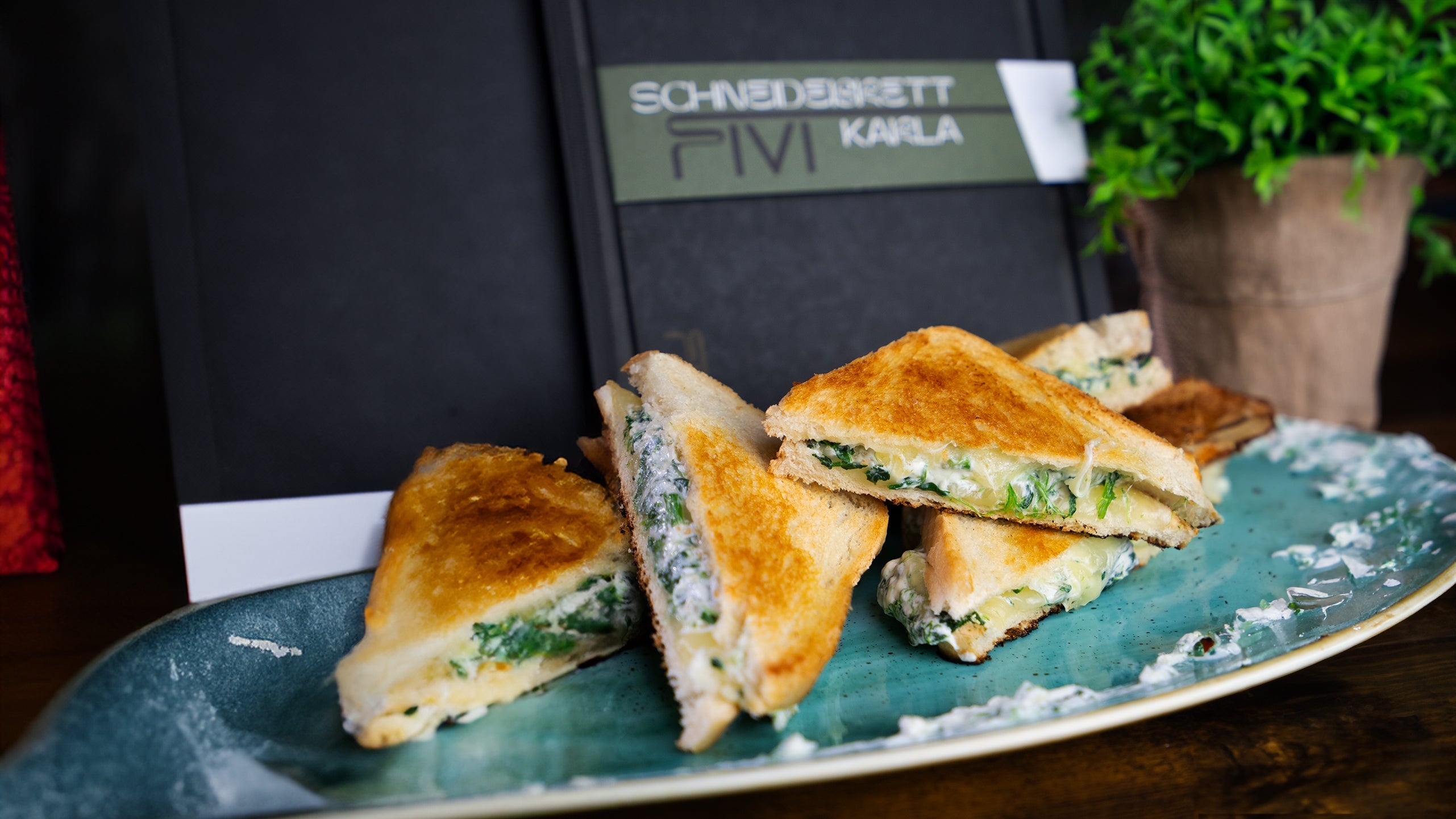 Knusprige Grilled Cheese Sandwiches gefüllt mit Spinat auf einem blauen Teller.