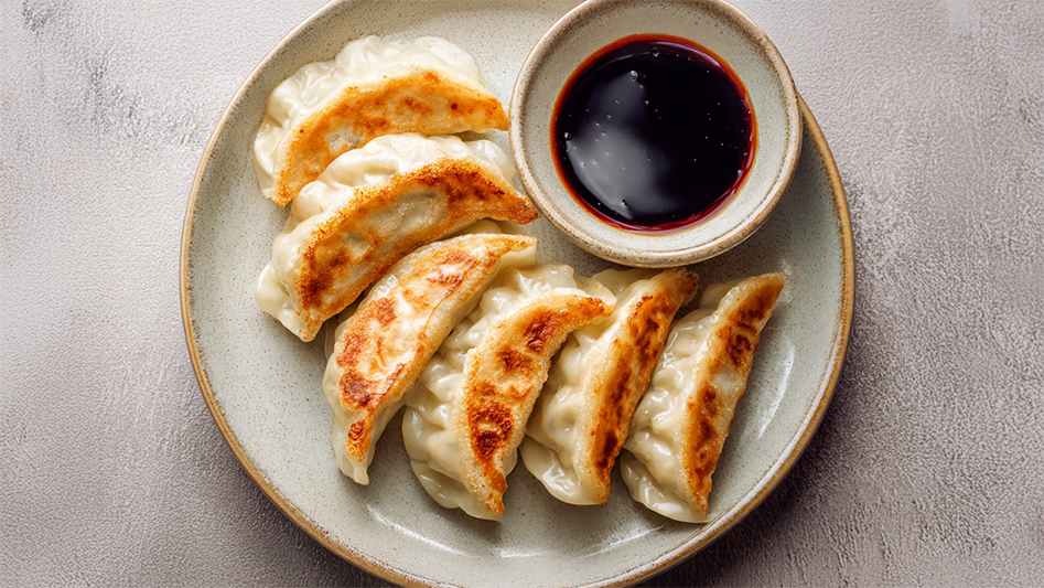 Gyoza Rezept – Knusprig gebratene japanische Teigtaschen mit Sojasauce-Dip auf hellem Teller angerichtet