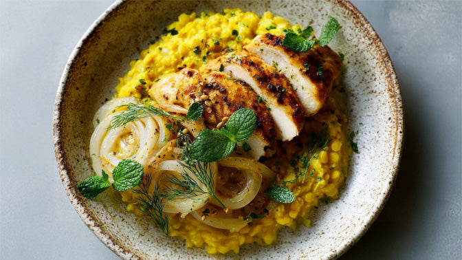 Kurkuma-Linsen mit Hähnchen von oben – angerichtetes Hähnchenfilet auf Kurkuma-Linsen mit Fenchelringen, Dillgrün und Minze aus der Draufsicht fotografiert.