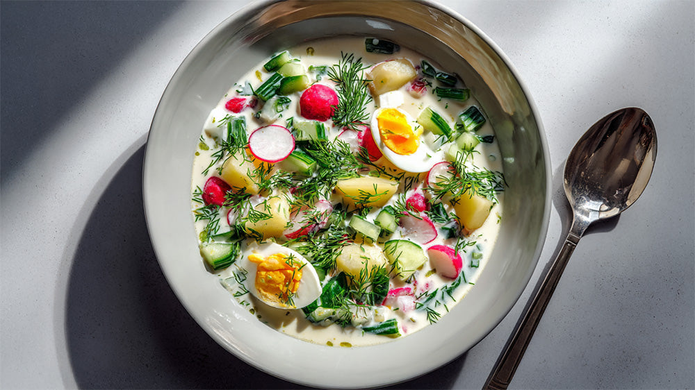 Draufsicht einer Schale Okroschka-Suppe mit Ei, Radieschen und Dill.