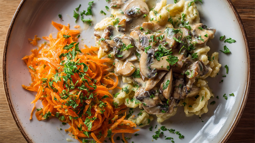 Spätzle mit cremiger Champignonrahmsauce und frischem Möhrensalat, garniert mit Petersilie