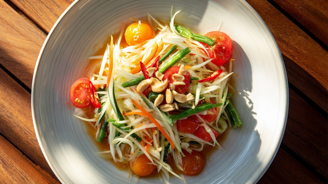Thai Papaya Salat angerichtet mit knackigen Bohnen, Chilischoten, Tomaten und gerösteten Erdnüssen