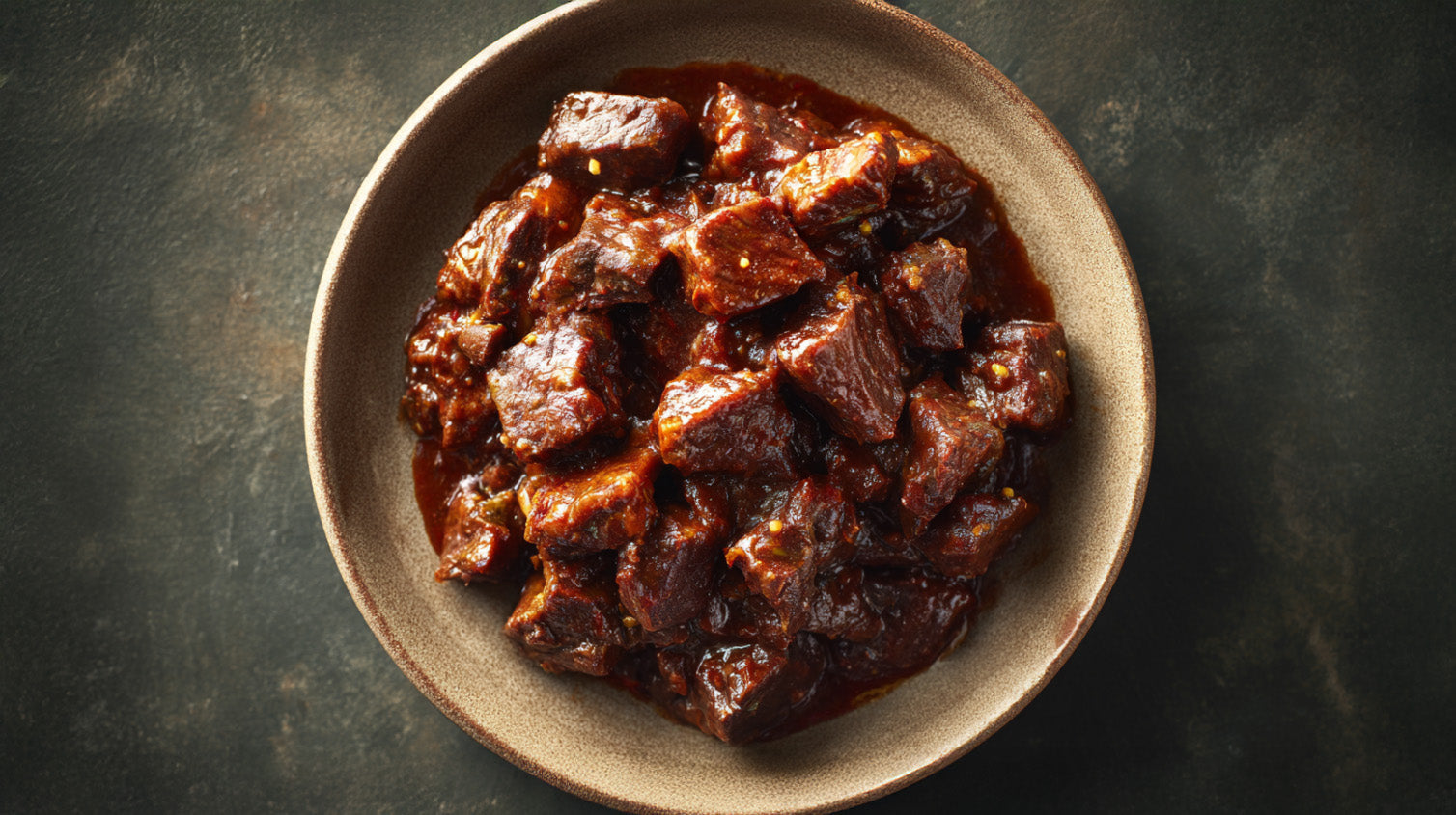 Wildgulasch in Schüssel, zart geschmorte Wildfleischwürfel in dunkler Rotweinsauce, rustikal angerichtet auf dunklem Hintergrund