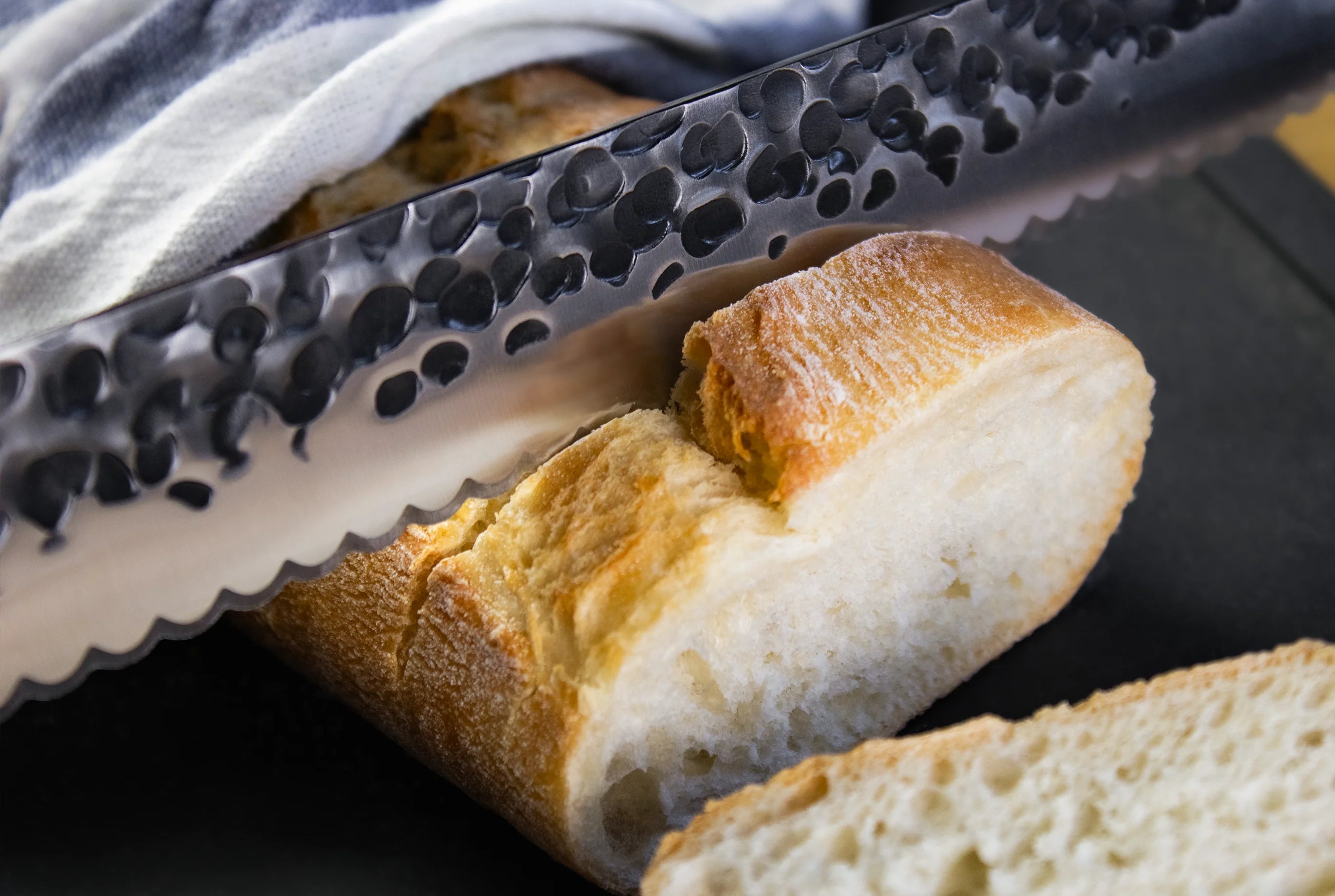 Das FIVI Messer Bernd, das ein Baguette auf einem FIVI Brett schneidet