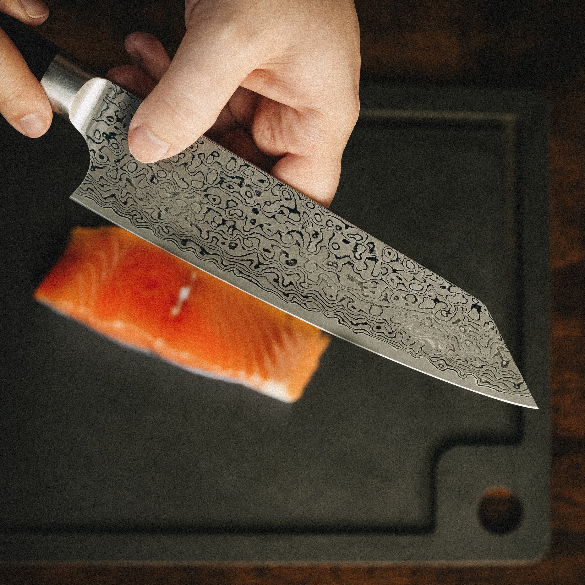 Ein Profikoch bereitet frischen Lachs mit dem scharfen Yuno Kiritsukemesser auf einem Schneidebrett zu.