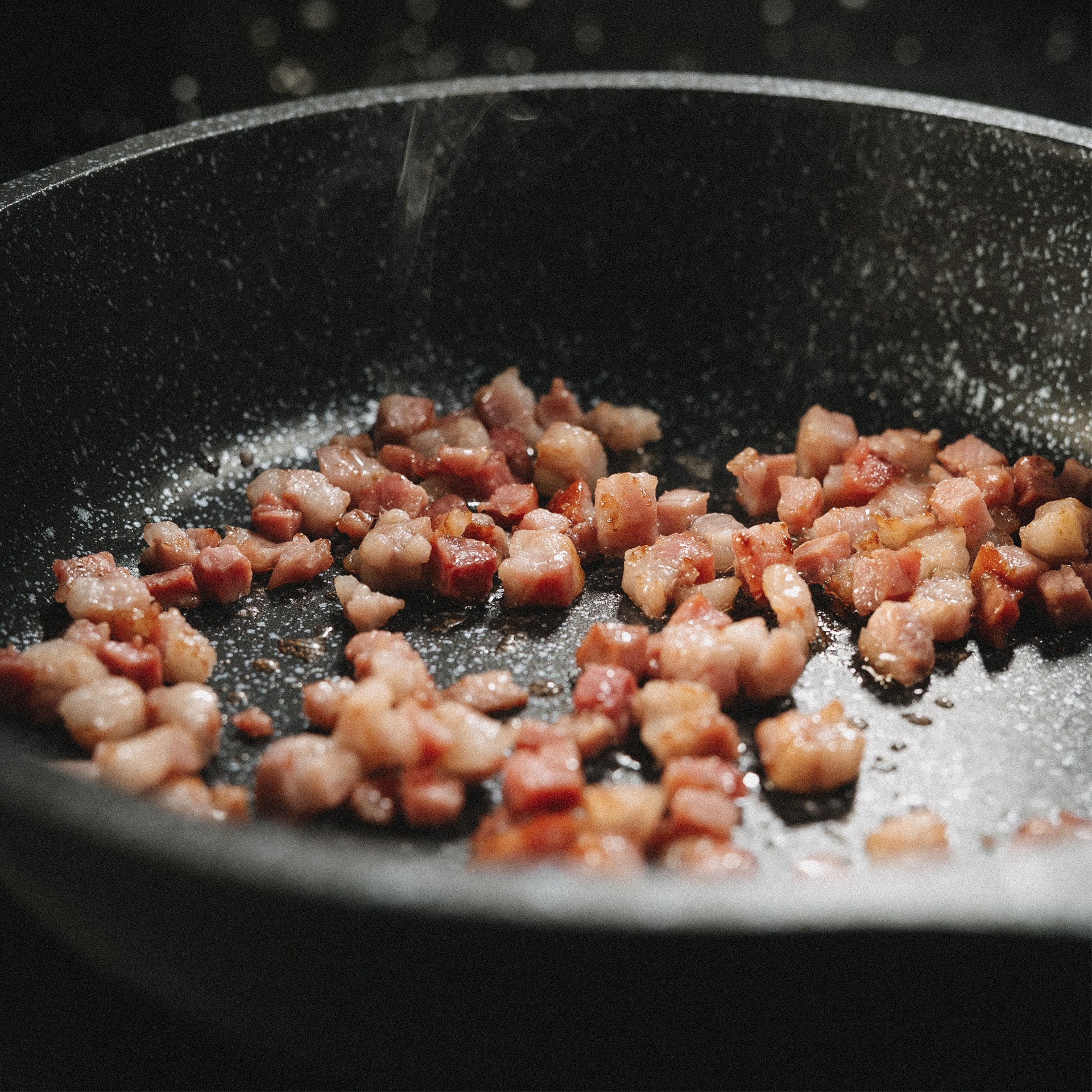 Brutzelnde Speckwürfel in einer heiß beschichteten Bratpfanne Utz während der Zubereitung.