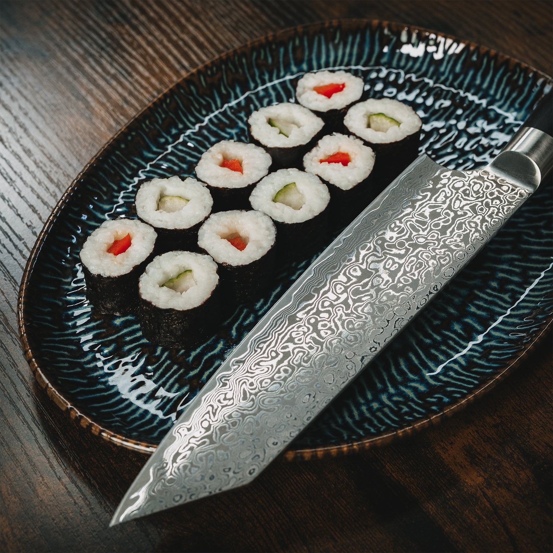 Detailansicht des Yuno Damastmessers neben einer Servierplatte mit Sushi Maki.