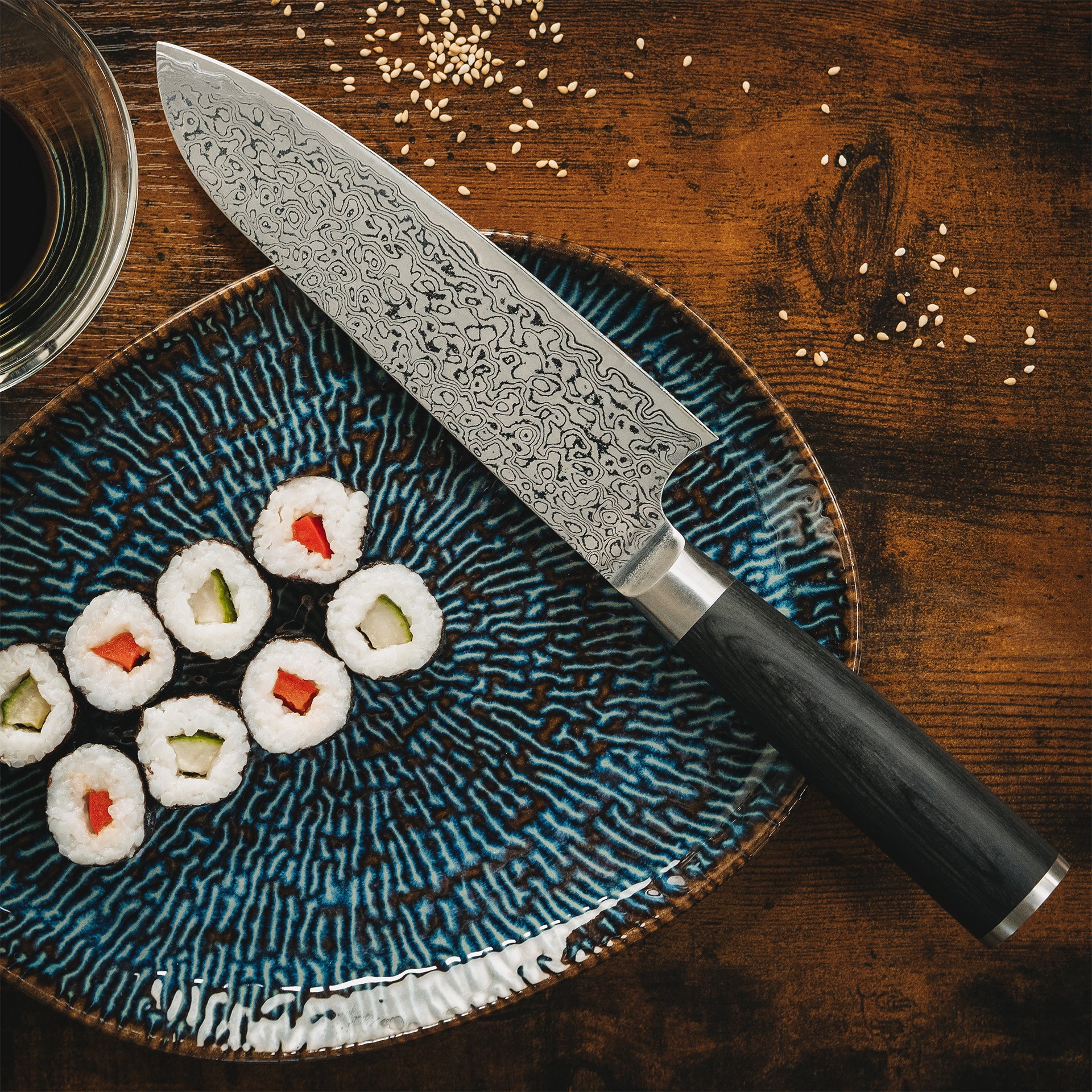 Draufsicht: Akira Damastmesser neben frischem Sushi auf Keramiktellern.