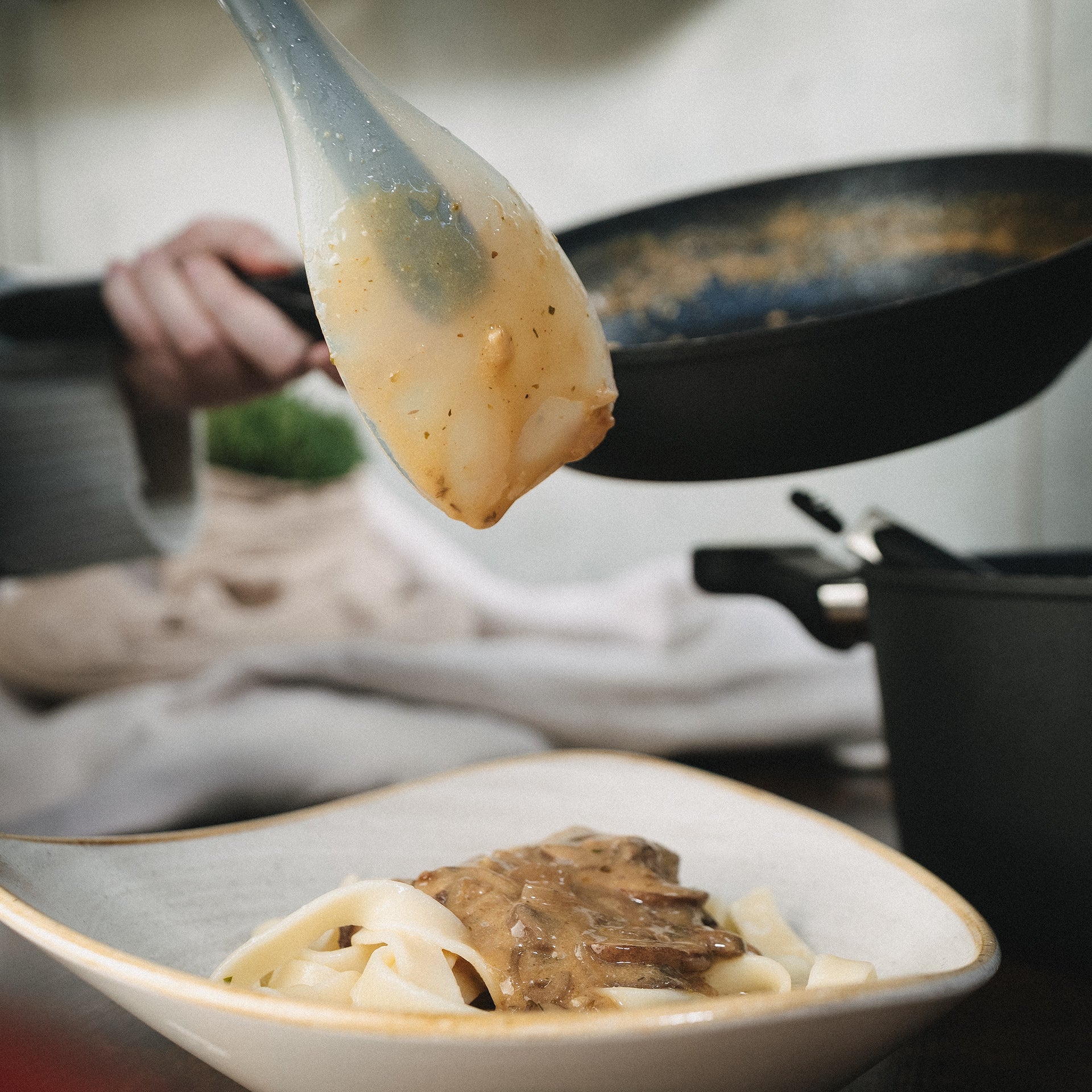 Der Stoneline Silikonlöffel füllt Sauce auf eine Portion Nudeln.