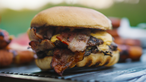 Saftiger Bacon-Cheeseburger in Nahaufnahme mit geschmolzenem Käse und knusprigem Bacon, serviert auf einem schwarzen Teller