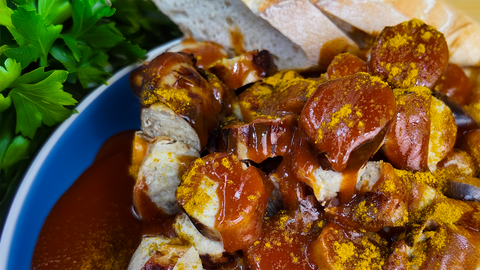 Knusprige Currywurst mit FIVI Curry Sauce und Currypulver, serviert mit frischem Baguette – ein deutscher Klassiker perfekt für Grillabende.