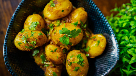 Bombay-Kartoffeln mit Kreuzkümmel, Kurkuma und Garam Masala, goldbraun gebraten und mit frischer Petersilie garniert – ein würziges, aromatisches Kartoffelgericht.