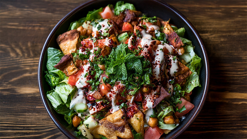 Draufsicht auf eine Schüssel Fattoush-Salat mit Minze und knusprigem Fladenbrot.