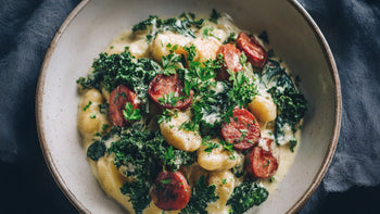 Gnocchi-Pfanne mit cremiger Blumenkohlsauce, veganer Salami und frischem Grünkohl – veganes Soulfood Rezept für ein schnelles Abendessen.