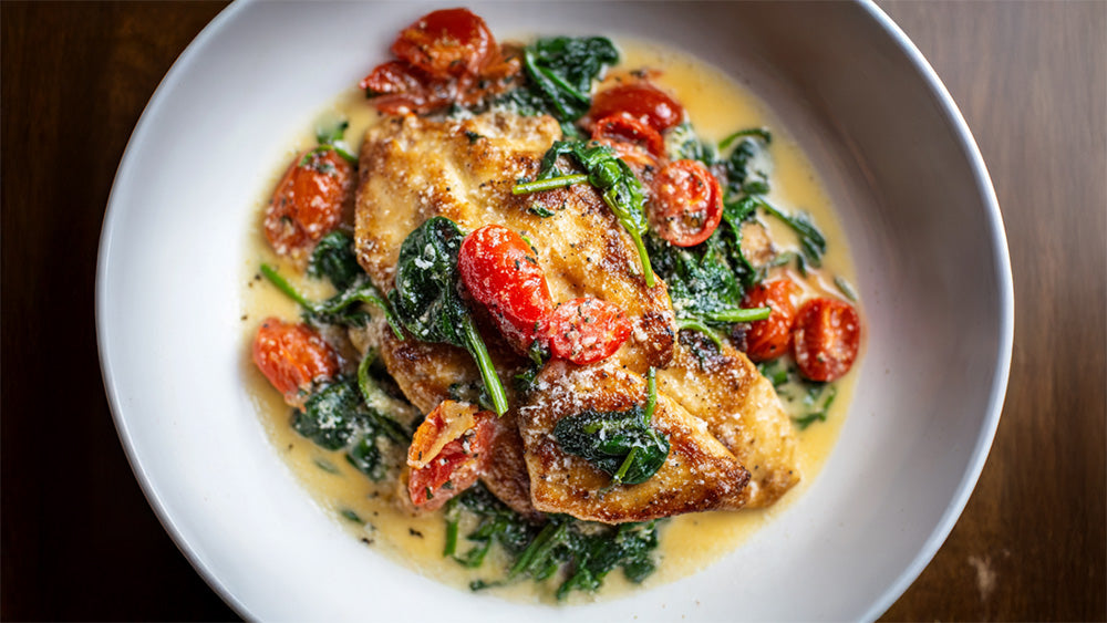 Hähnchenpfanne mit Spinat und Parmesan in cremiger Sauce, saftiges Hähnchen mit Tomaten von oben fotografiert