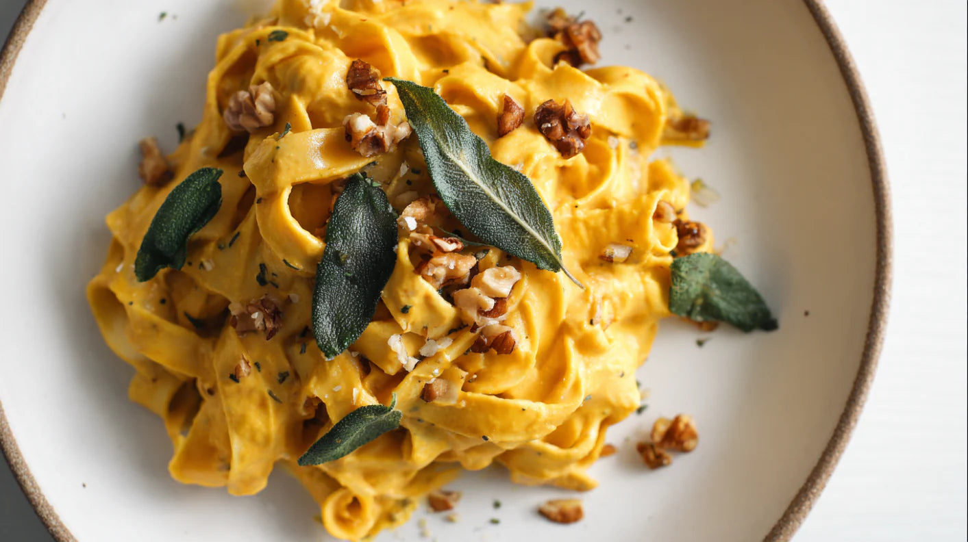 Kürbispasta mit cremiger Sauce, frischem Salbei und Walnüssen – veganes Pasta-Rezept auf weißem Teller