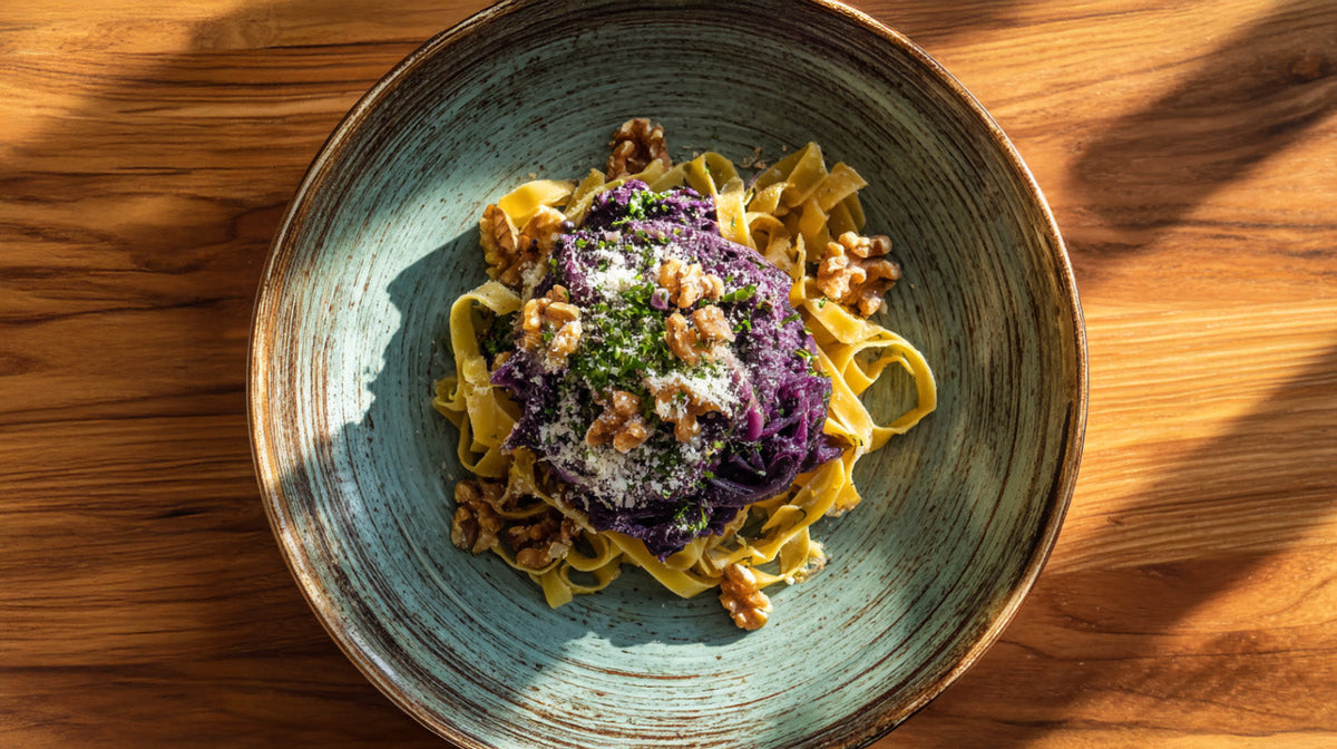 Tagliatelle mit lila Pesto aus Rotkohl auf grünem Teller, garniert mit Walnüssen und Parmesan – kreatives Halloween-Pasta-Gericht auf Holztisch.