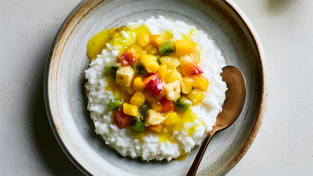 Draufsicht auf Milchreis mit exotischem Obstsalat in einer Schale.