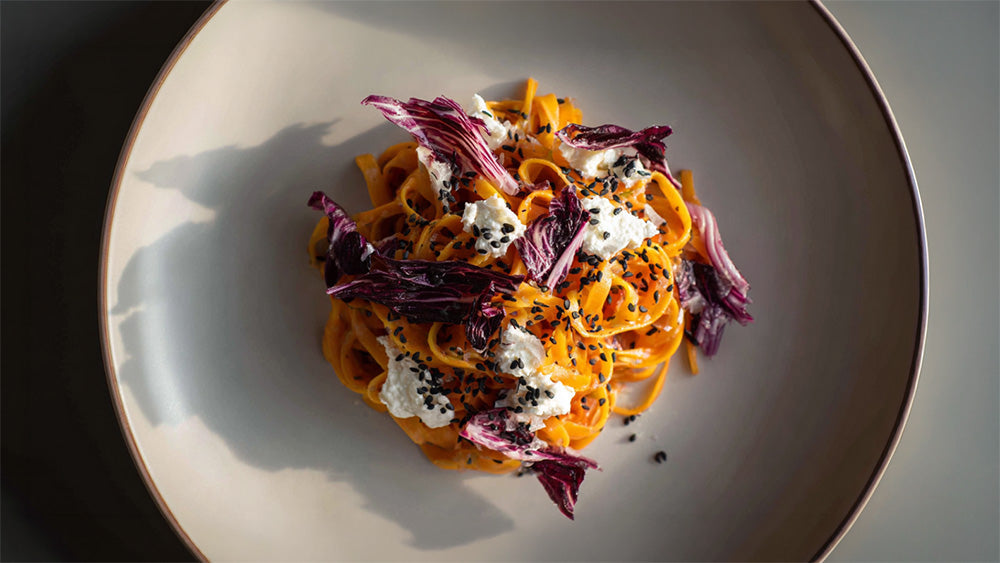 Möhren-Linguine mit Radicchio auf Teller angerichtet, cremige Pasta mit Ricotta und Schwarzkümmel