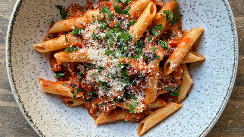 Pasta Arrabbiata mit Penne, feuriger Tomatensauce, frischen Kräutern und Parmesan – würziges italienisches Gericht auf einem Teller serviert.