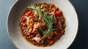 Kaninchen-Ragout mit roten Linsen, Möhren und Sellerie, angerichtet in einer hellen Schale, verfeinert mit frischen Kräutern