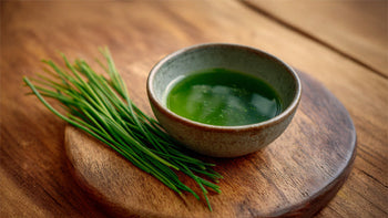 Schnittlauchöl in Schale auf Holzbrett mit frischen Schnittlauhalmen daneben – leuchtend grün und ideal dargestellt für Rezept und Foodblog.