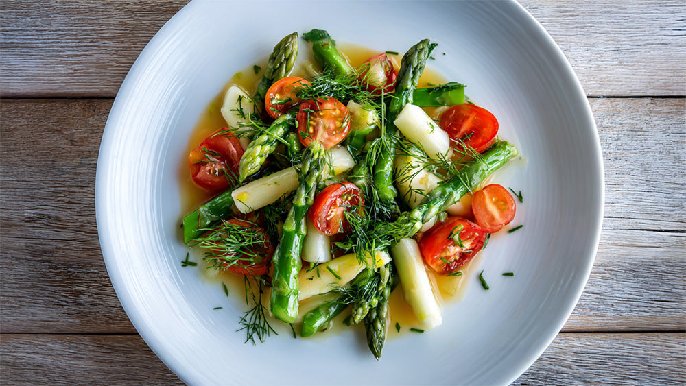 Lauwarmer Spargelsalat mit grünem und weißem Spargel, Cherrytomaten und frischem Dill auf weißem Teller von oben fotografiert