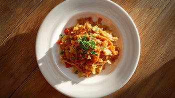 Spitzkohlpfanne mit Nudeln auf weißem Teller von oben fotografiert, garniert mit frischer Petersilie