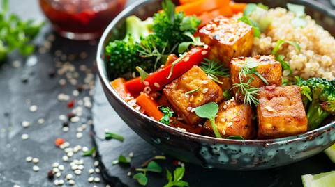 Knuspriger Tofu mit frischem, bunten Gemüse und Quinoa in einer dunklen Schüssel.