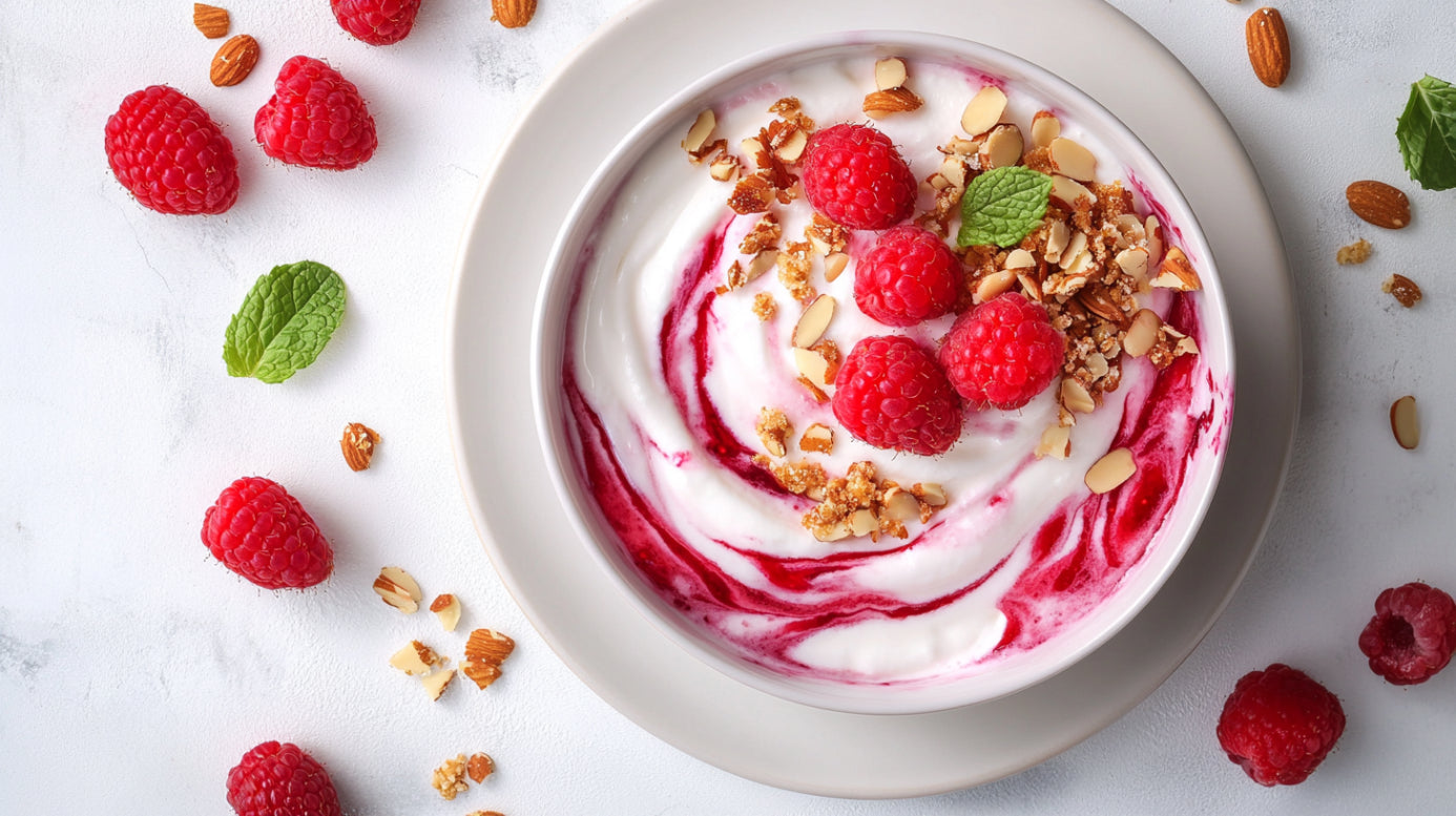 Vanillequark mit Beeren und Mandelcrunch – cremiges Dessert mit Himbeeren, gerösteten Mandeln und Minze in weißer Schale angerichtet