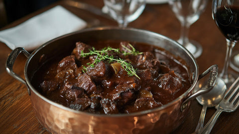 Nahaufnahme von zartem Wildgulasch in reichhaltiger Soße, serviert im Kupfertopf – ein Genuss für die Winterküche.