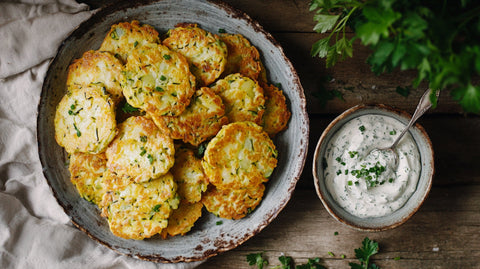 Knusprige Zucchini-Kartoffel-Puffer mit frischen Kräutern auf einem rustikalen Teller, serviert mit cremigem Kräuterdip – gesund, lecker und perfekt gebraten.