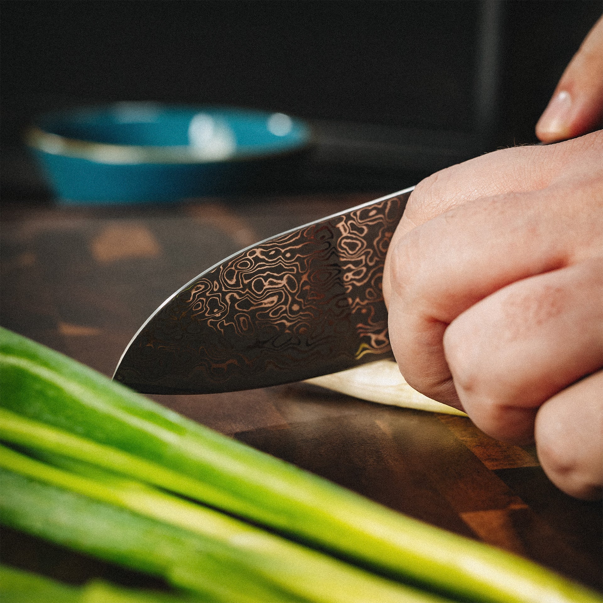 Profikoch schneidet Frühlingszwiebeln mit dem scharfen Akira Santokumesser auf einem Holzbrett.
