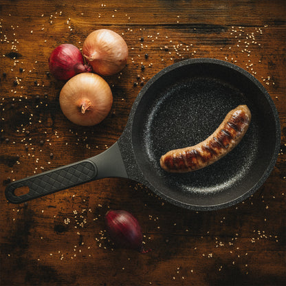 Bratpfanne Utz auf rustikalem Holztisch mit gebratener Wurst, Zwiebeln und Gewürzen.