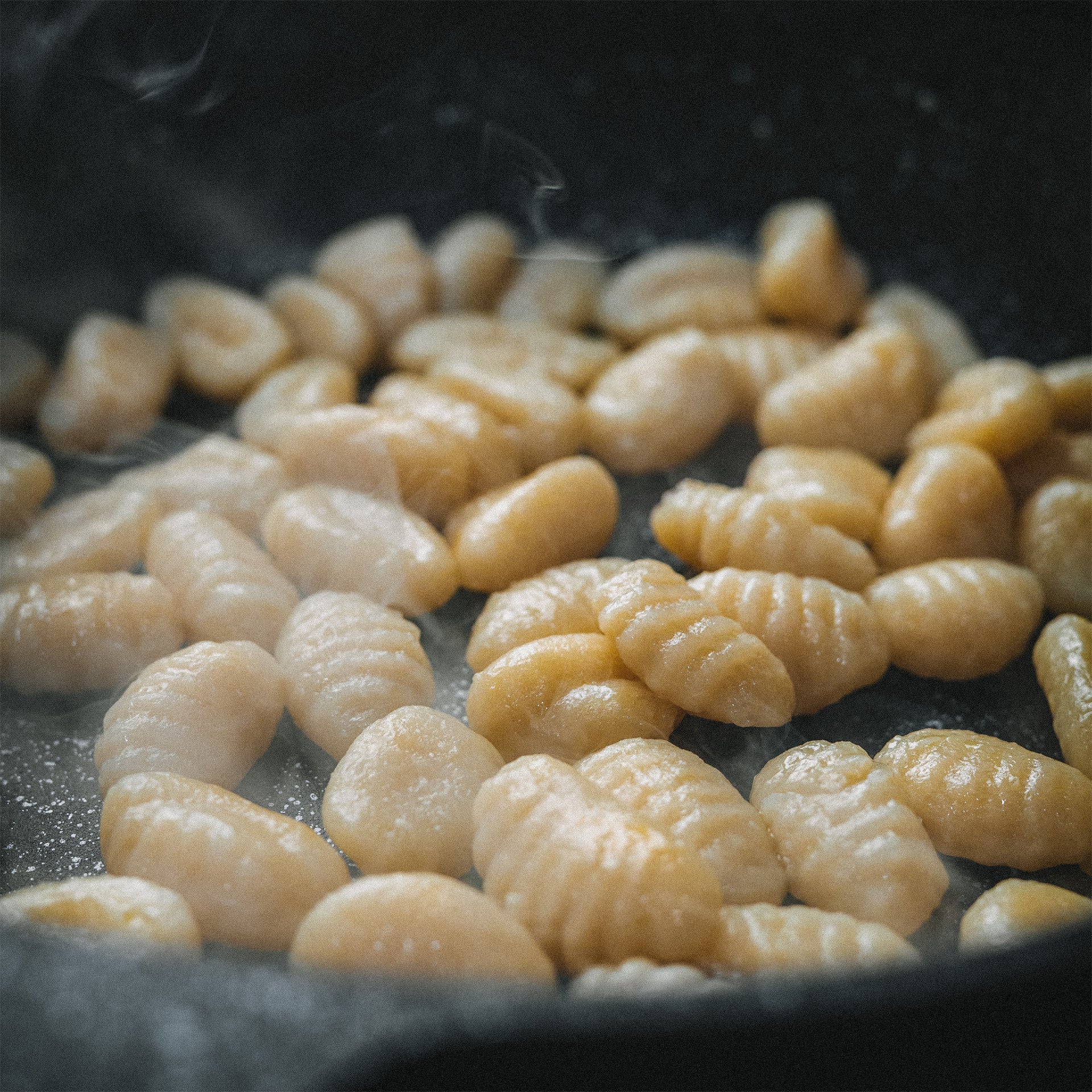 Goldbraun angebratene Gnocchi in der heißen Pfanne Almar mit leichter Dampfentwicklung.