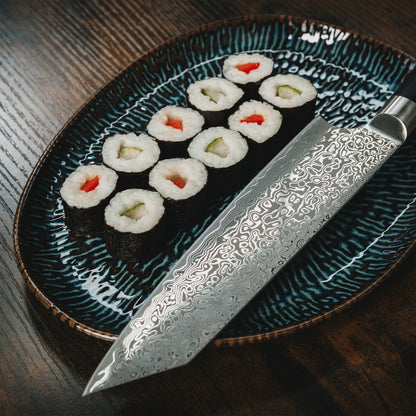Detailansicht des Yuno Damastmessers neben einer Servierplatte mit Sushi Maki.