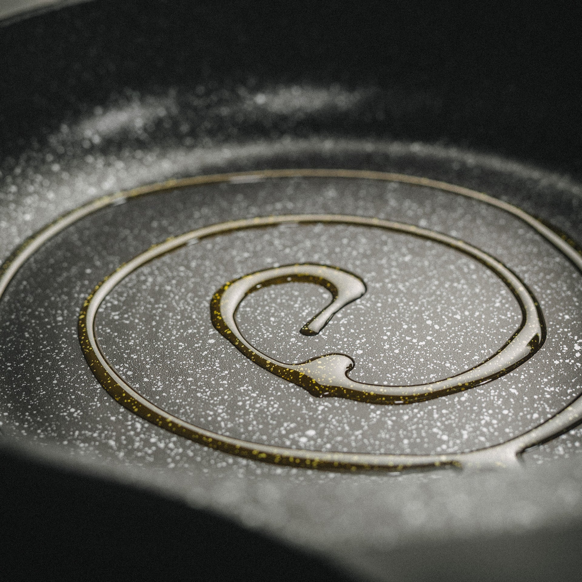 Nahaufnahme der hochwertigen Antihaft-Pfanne Vanessa mit Beschichtung und einem Schuss Speiseöl.