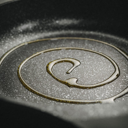 Nahaufnahme der hochwertigen Antihaft-Pfanne Vanessa mit Beschichtung und einem Schuss Speiseöl.