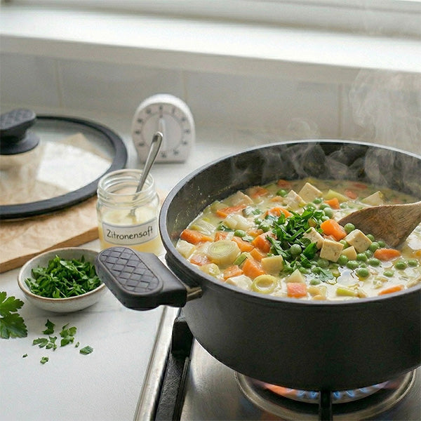 Fertiger Gemüseeintopf mit Tofu, garniert mit frischer Petersilie. Daneben ein Glas Zitronensaft, eine Schale gehackte Petersilie und eine Eieruhr.